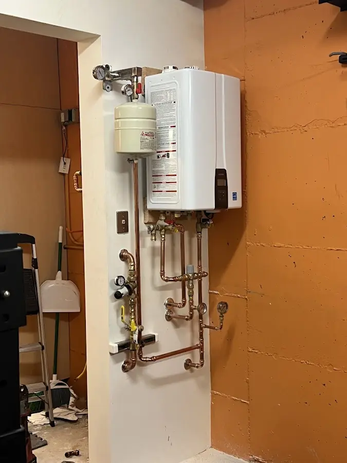 Plumbing technician inspecting water heater connections in Egg Harbor